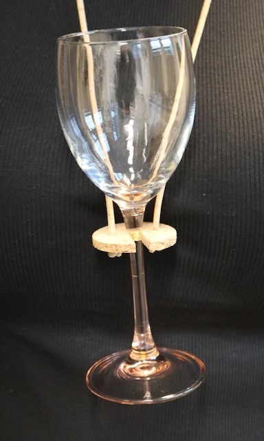 Weinglashalter aus Kork mit Glas und dunklem Hintergrund.