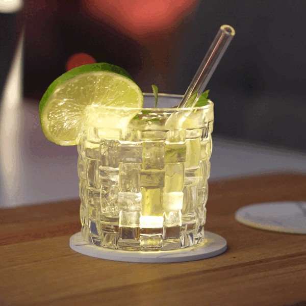 Glas mit Zitrone auf gelbem LED Leuchtuntersetzer