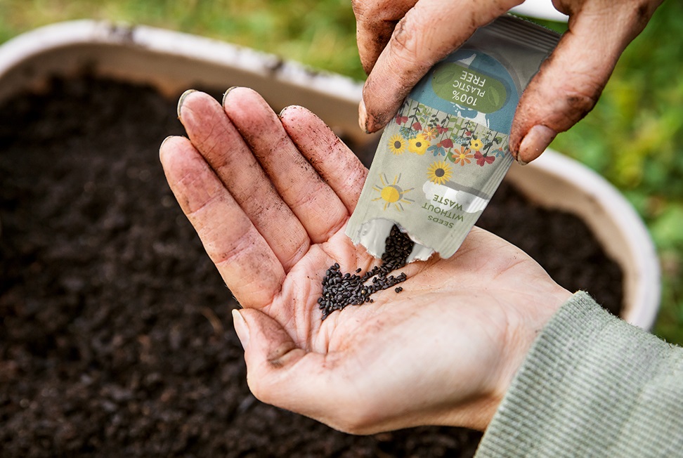 Plastikfreie Samentüte mit Hand und Blumenerde.