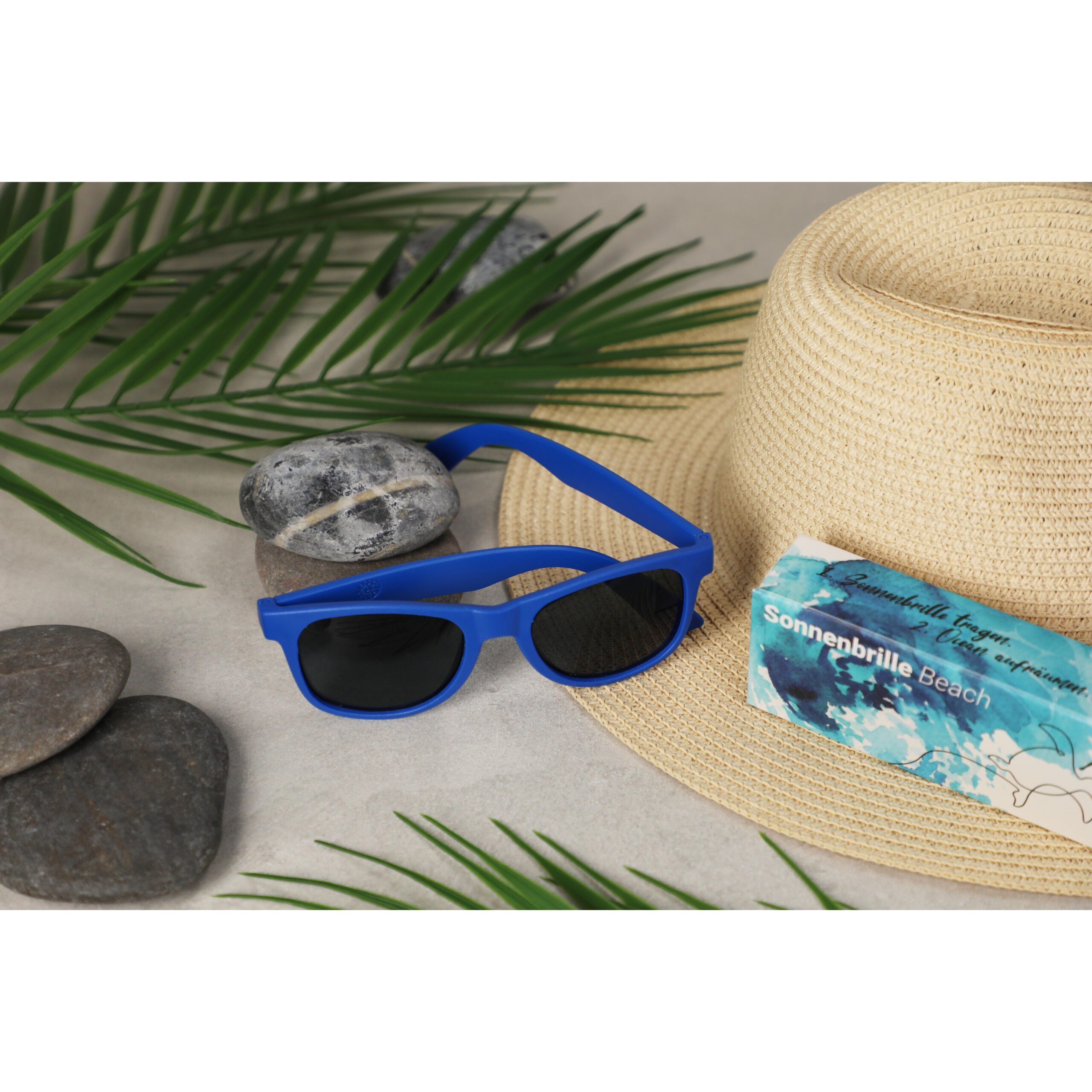 Blaue Sonnenbrille mit Hut am Strand